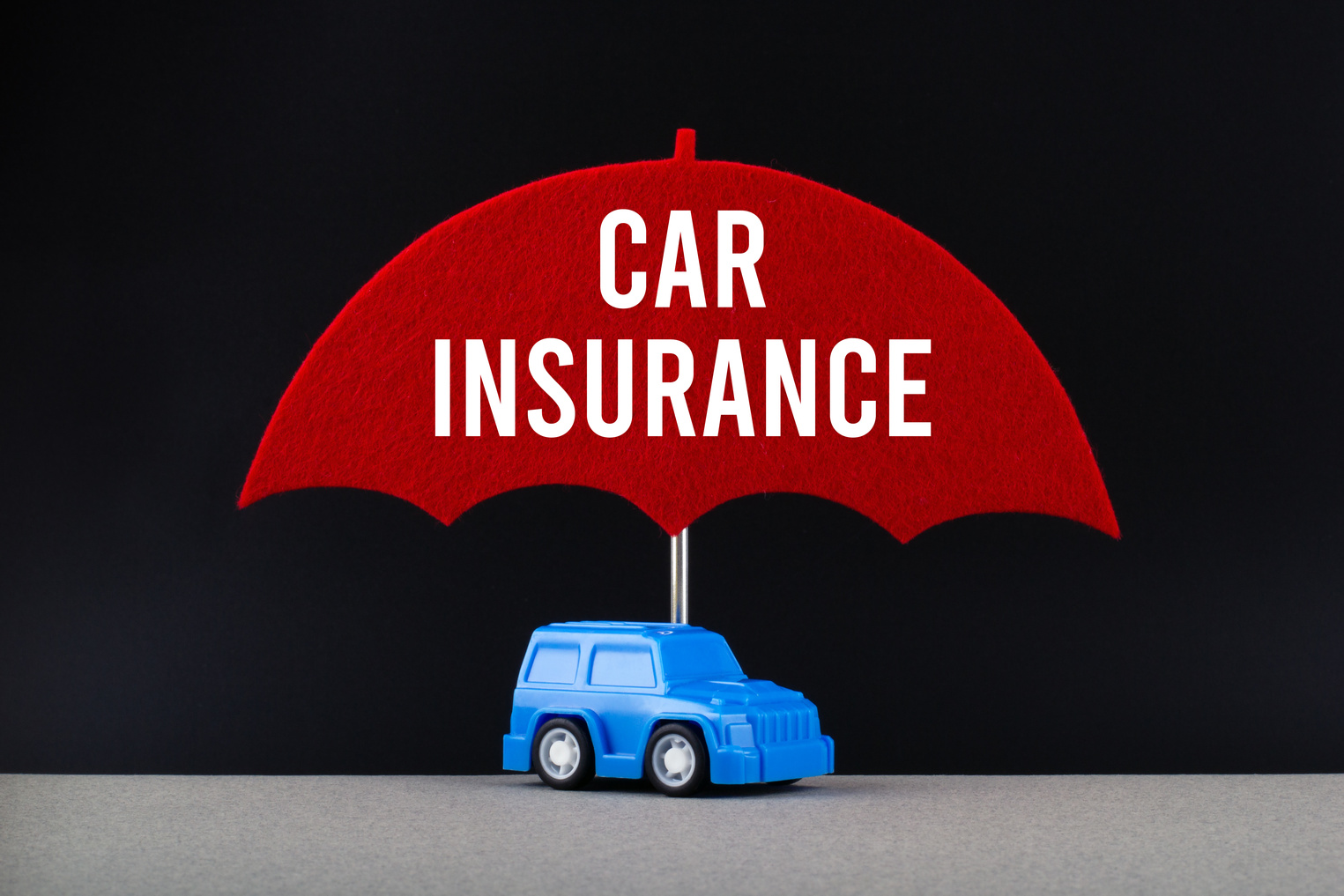 Concept of car insurance. Blue car under red umbrella with text Car insurance.